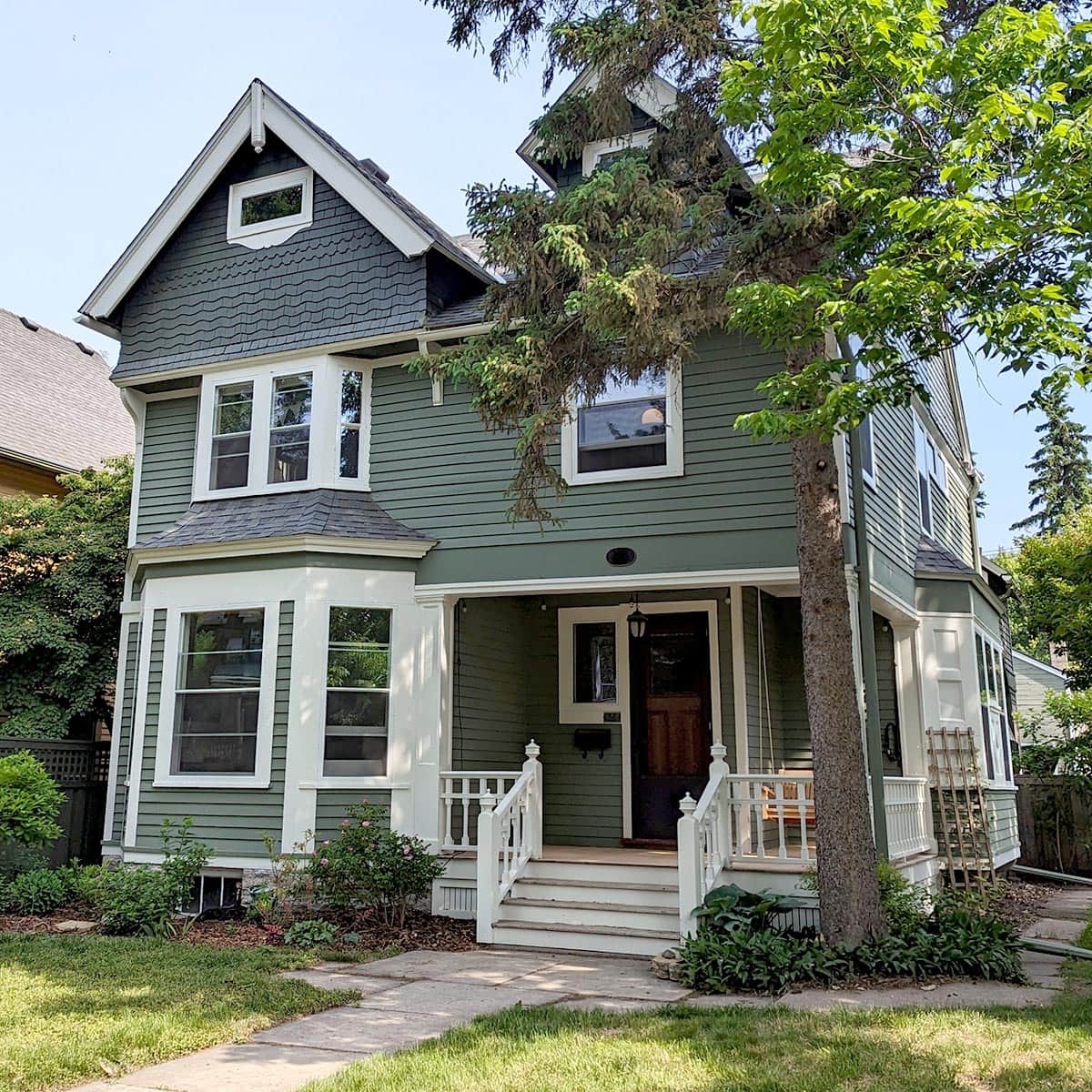 Hayes-Window-Restoration-McCormick-Drinan-Main-1-SQ Charming green two-story Victorian house with white trim.