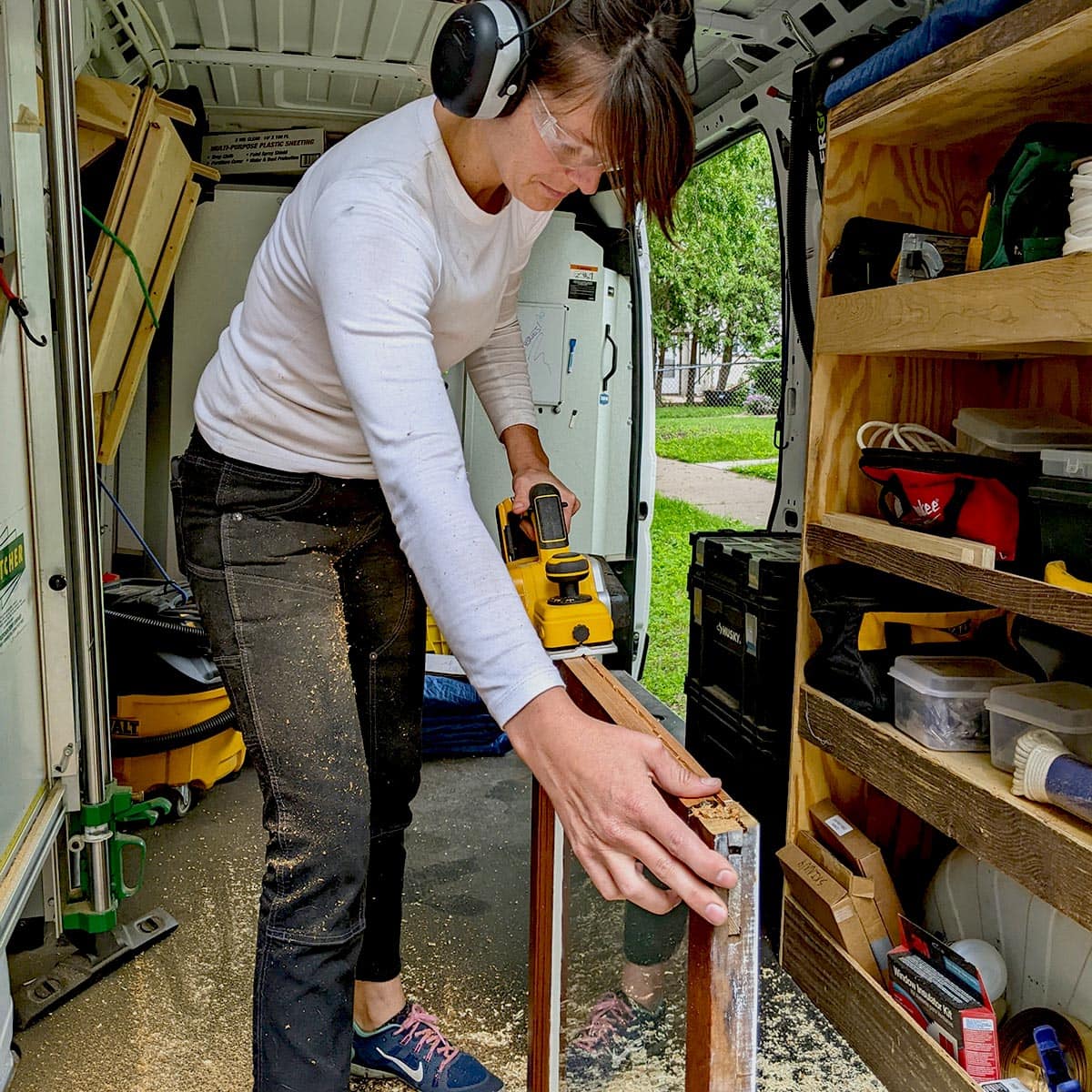 Hayes-Window-Restoration-Services-Header-1-SQ Woman using power planer in van workshop setup.