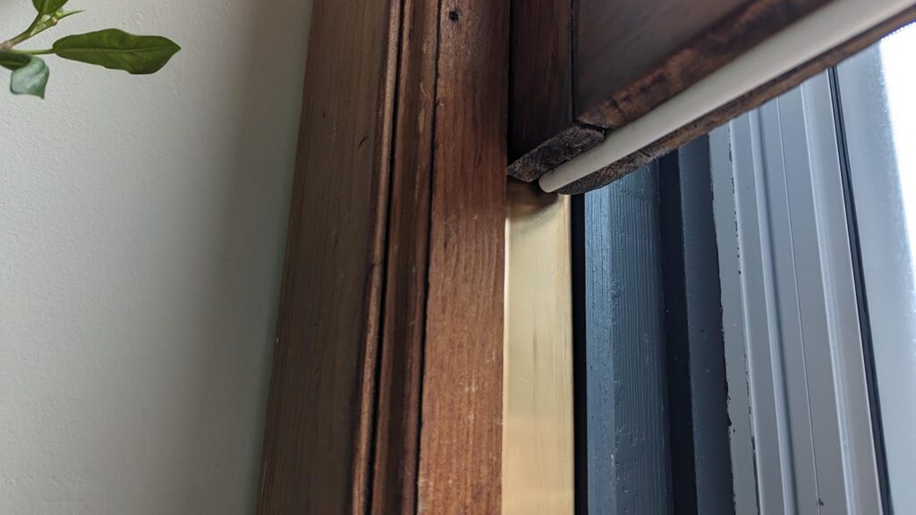 Window blind mechanism with wooden frame and leaf detail.