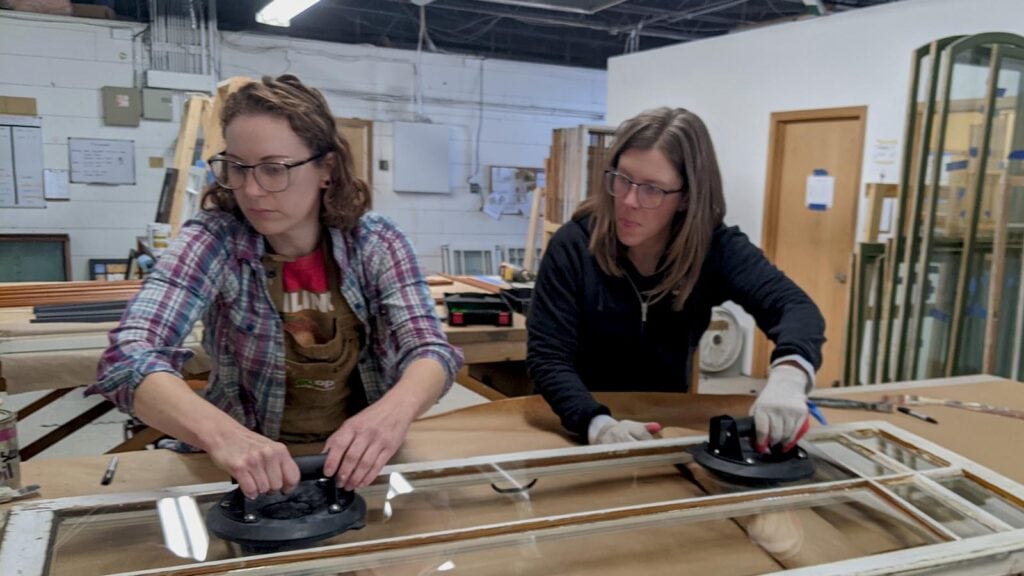 Two women assembling windows in a workshop.