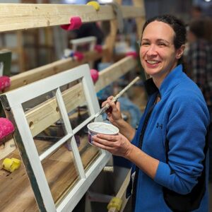 Woman painting a wooden frame in a workshop.