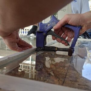 Person using a staple gun on window frame.