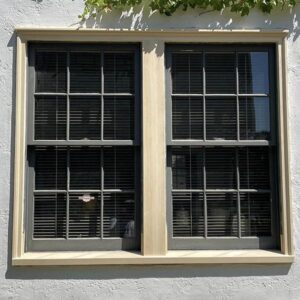 Double window with black shutters on white wall.