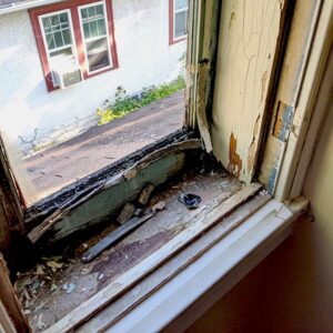 Decayed window sill with visible damage and debris.