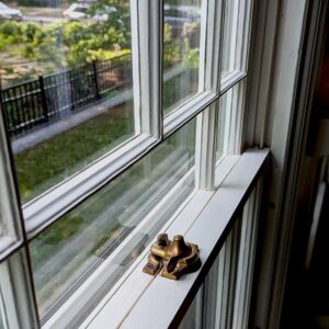 Old brass window lock on a white framed window.