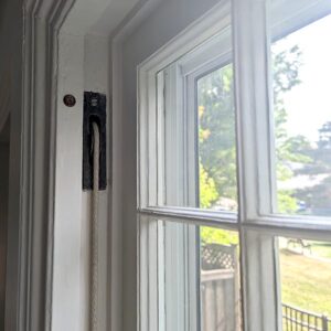 White window frame with outdoor view and cord.