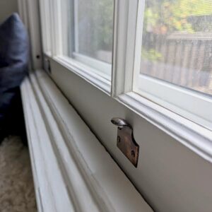 Close-up of window latch on white frame.