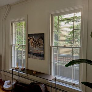 Cozy room with windows, art, and plant.