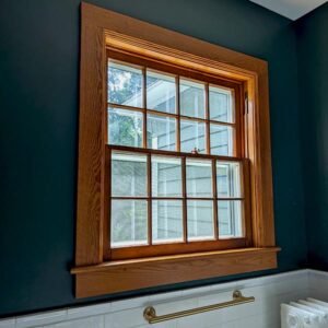 Wooden framed window in dark blue room with sunlight.
