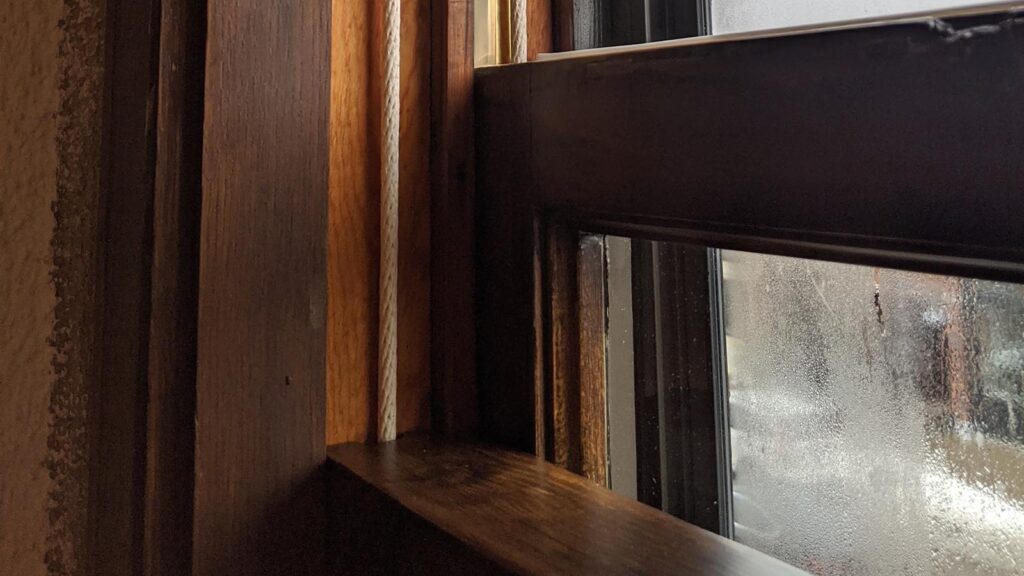 Foggy window with wooden frames and sunlight streaming in.