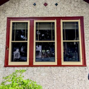 Red-trimmed windows on textured stucco wall.