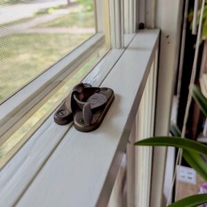 Vintage window lock on a white sill, indoor setting.