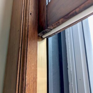 Snake hiding in wooden window frame corner.