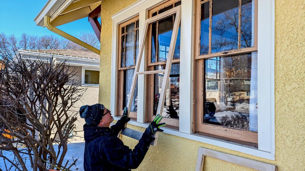 Worker installing new window in sunny winter setting.