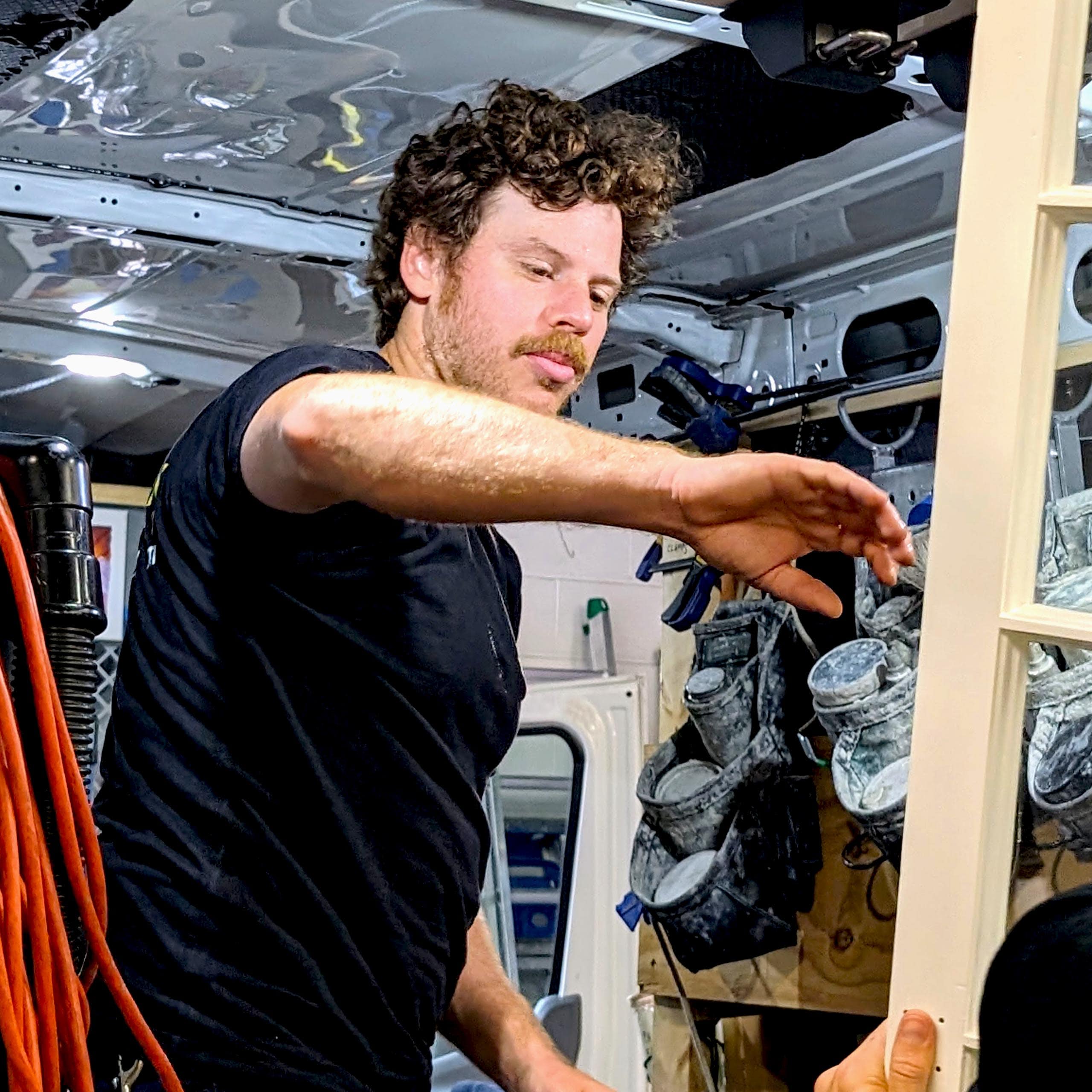 Man installing door in van conversion workshop