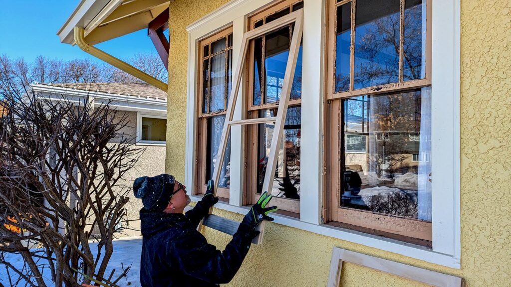 Person repairing wooden storm window frame on sunny day