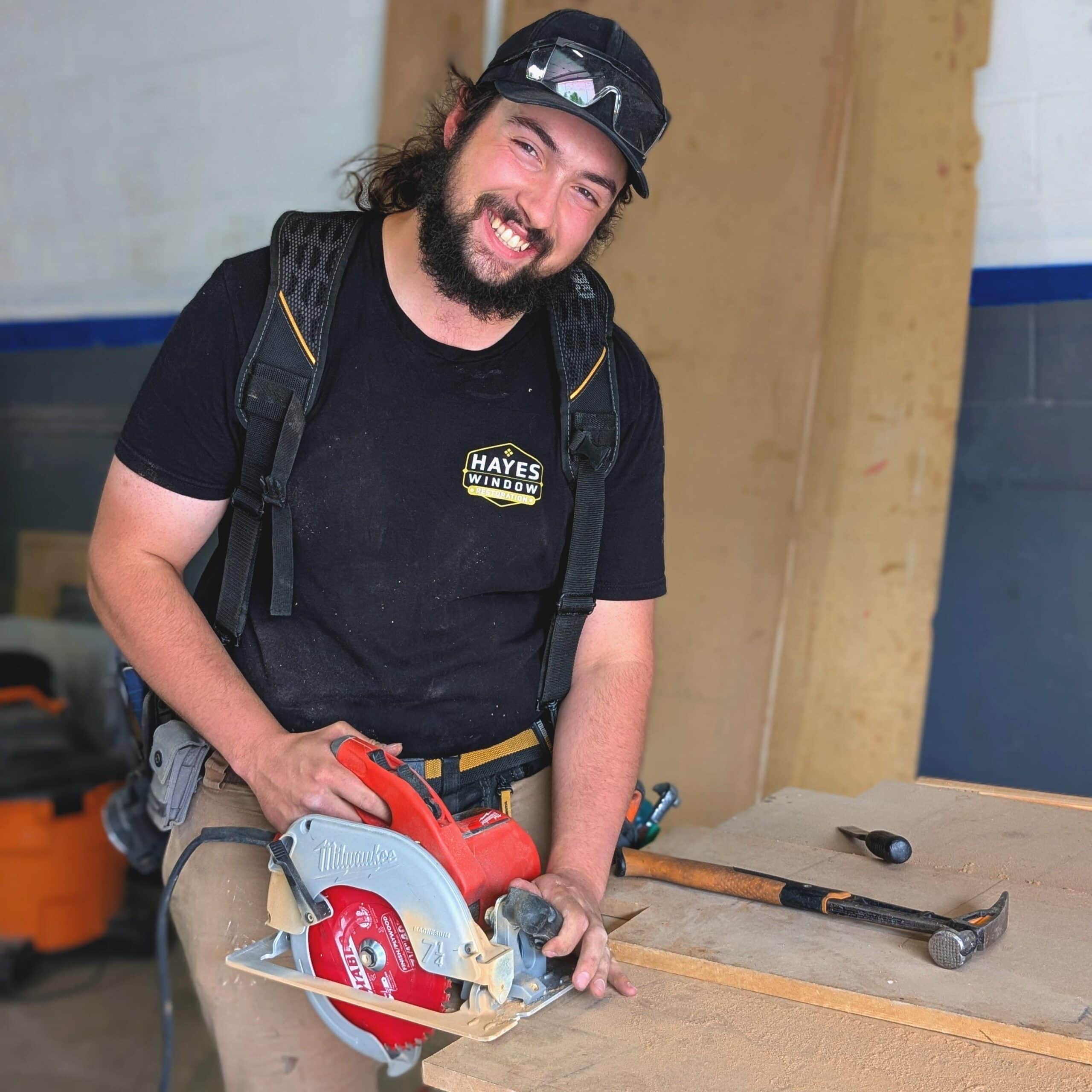 A man with a beard and a hat is using a circular saw.