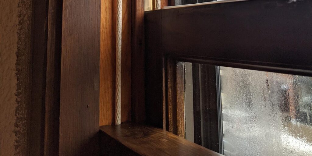 Foggy window with wooden frames and sunlight streaming in.