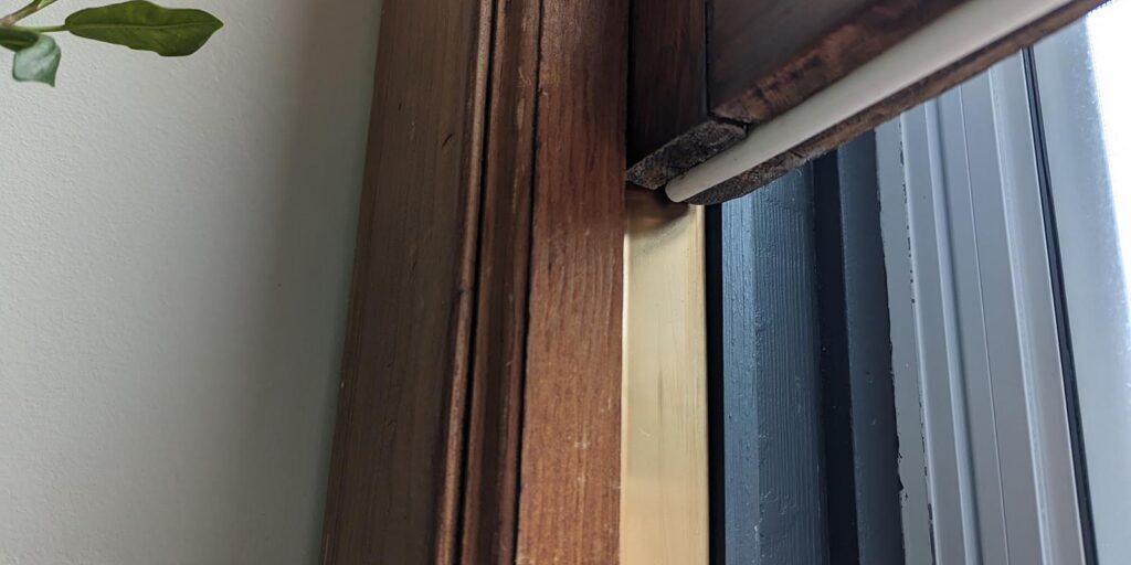 Window blind mechanism with wooden frame and leaf detail.