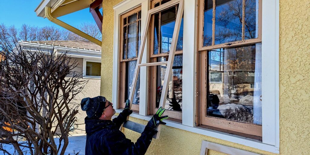 Person repairing wooden storm window frame on sunny day